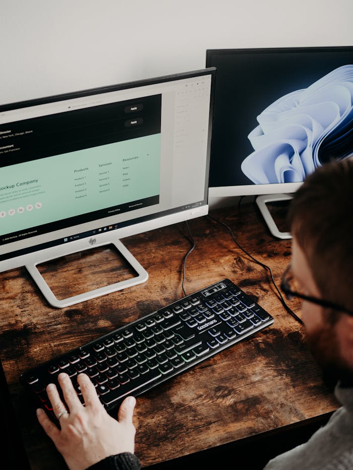 services-02 Adult man uses dual monitors for web design in a home office setting.